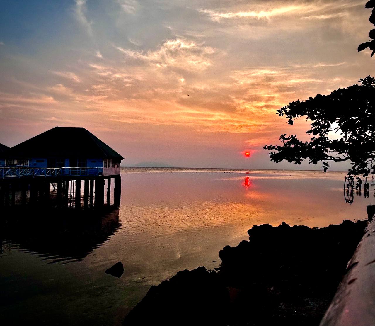 Travel reward — sunset over a stilt house by the sea